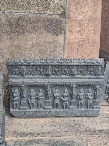 A rectangular panel contains two horizontal rows of figures, separated by carved bands. Small column-like divisions organise the lower row.