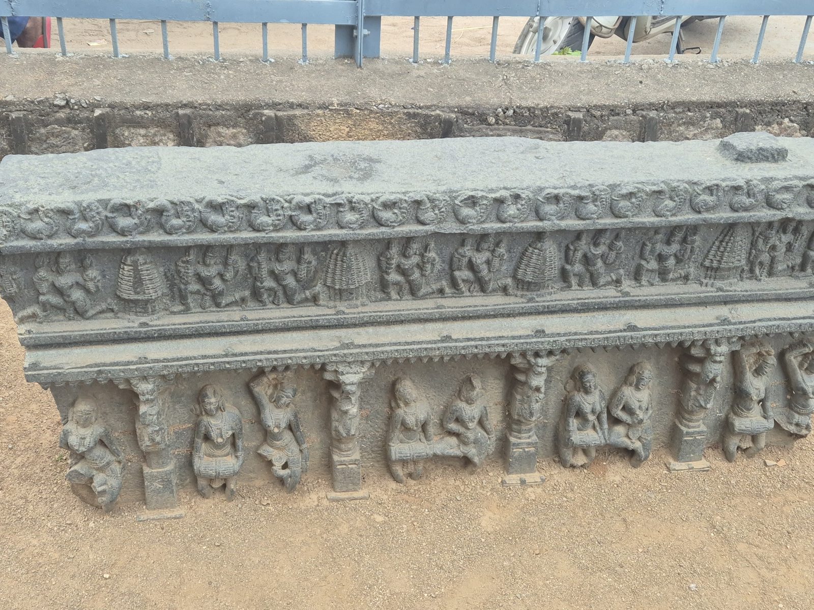 A long horizontal fragment carries a narrow upper frieze and a lower sequence of figures between carved supports. Its right edge extends beyond one photograph.