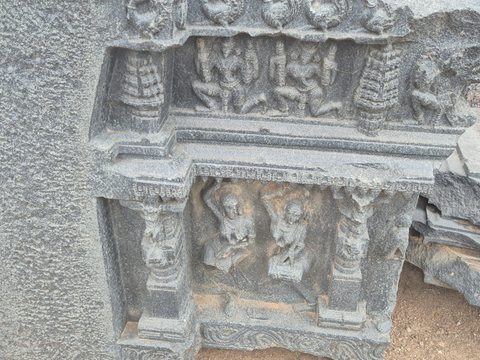 Small figures sit within two levels of framed recesses. An uneven broken edge interrupts the carving at the right.
