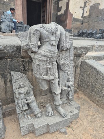 A headless figure stands with one leg bent. Jewellery, garment folds and smaller figures survive around the lower body.