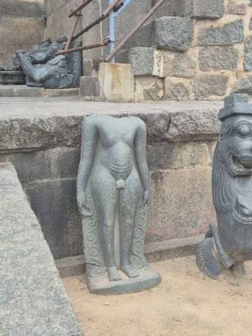 A slender standing body survives with both arms lowered. The head is missing; curls and ornament remain beside the legs.