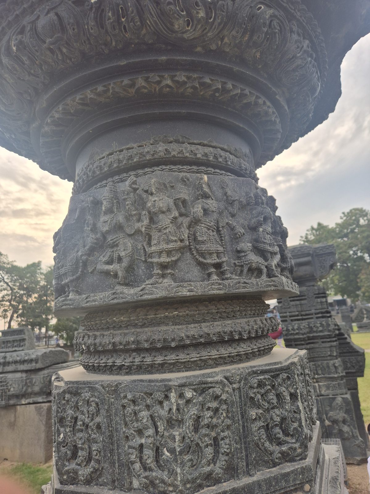 Rows of figures and fine patterned bands wrap around a rounded column. The upper and lower ends extend beyond the available views.