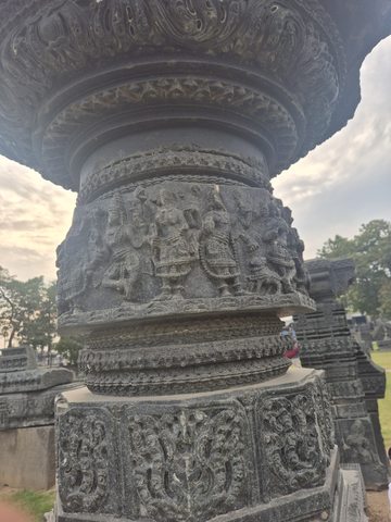 Rows of figures and fine patterned bands wrap around a rounded column. The upper and lower ends extend beyond the available views.