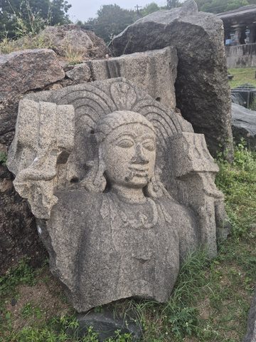 Another photograph of the same recorded subject. A face with large earrings emerges beneath radiating bands. Broken edges surround the head and upper body, with other stones visible behind.