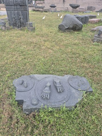 Two carved feet remain on a broken base with curved decorative bands. The rest of the figure is absent from this surviving piece.