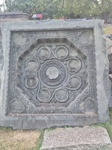 Another photograph of the same recorded subject. A ring of circular motifs surrounds a central disc inside an angular border. Scrolling ornament fills the outer corners of the square panel.