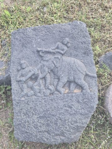 A large four-legged animal and smaller figures occupy the upper part of a roughly rounded slab. The surrounding field is visibly weathered.