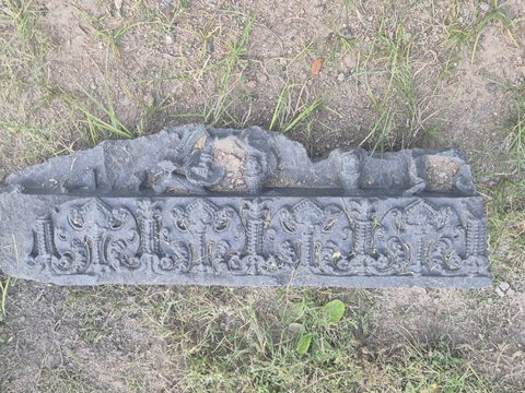 Repeated curling forms run along a horizontal fragment. Broken projecting forms survive along its upper edge.