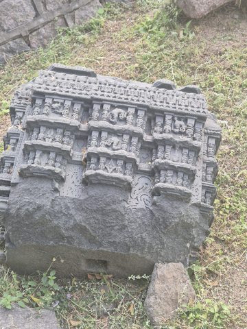 Repeated small recesses, figures and column-like forms cover the upper portion of a thick broken block.