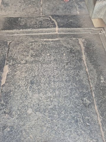 Closely spaced incised characters cover a rectangular slab within the stone floor. The text is not transcribed or translated here.