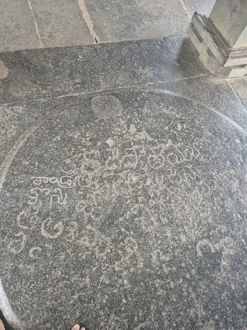 Rows of incised characters remain visible across a worn floor surface beside the base of a column. Its text and date are unverified.