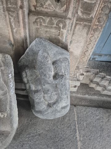 A rounded slab carries a worn elephant-headed figure. The headdress, trunk and bent legs remain visible, though some details are indistinct.