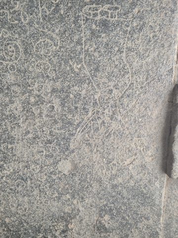 Shallow characters cover a worn stone surface. This close photograph does not establish the full shape of the inscribed object, and the text remains unread.