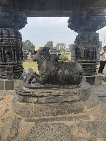 A reclining horned animal with carved ornament rests on a raised base between columns. A wider view records the surrounding assembly without establishing its original arrangement.