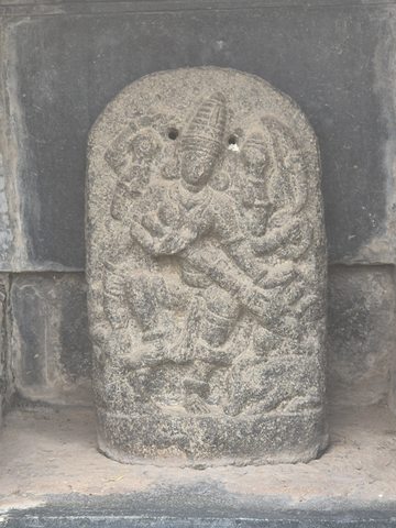 Several arms extend around a central figure on a rounded upright relief. Weathering has softened much of the surface detail.